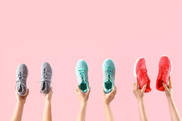 Γυναικεία Χέρια Που Κρατούν Διαφορετικά Αθλητικά Παπούτσια Ροζ Φόντο — Φωτογραφία Αρχείου