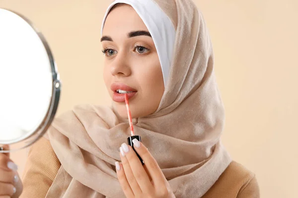 光の背景に唇の光沢を適用する鏡を持つ若いムスリム女性 — ストック写真