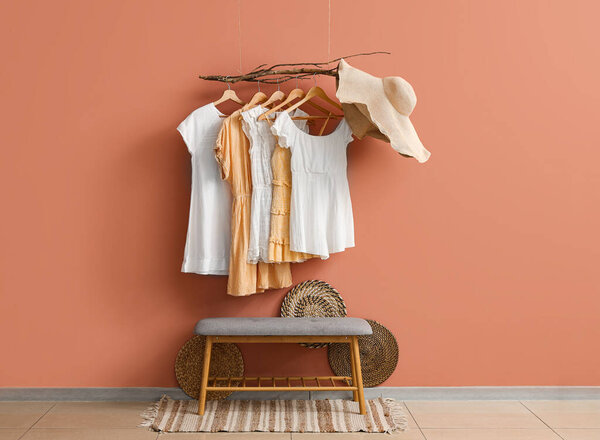 Bench and hanging clothes with hat near pink wall in hall