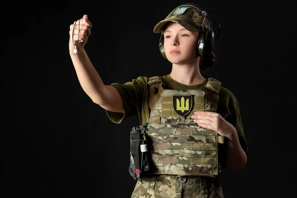 暗い背景にウクライナのトライデントペンダントを持つ若い女性兵士 — ストック写真