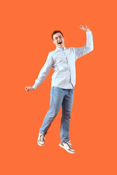 Glücklich Springender Junger Mann Auf Orangefarbenem Hintergrund — Stockfoto