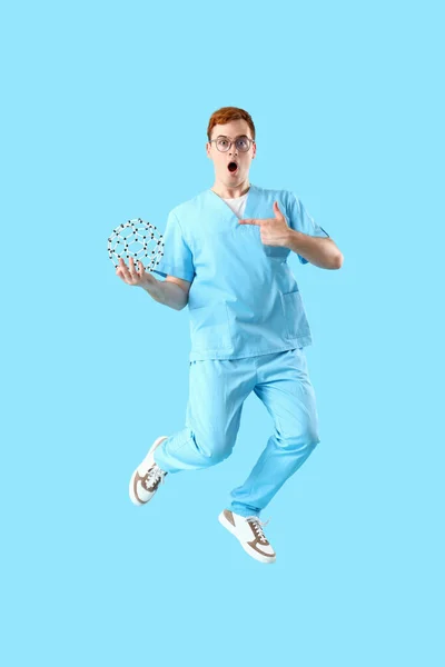 Jumping surprised male laboratory assistant with model of molecule on blue background
