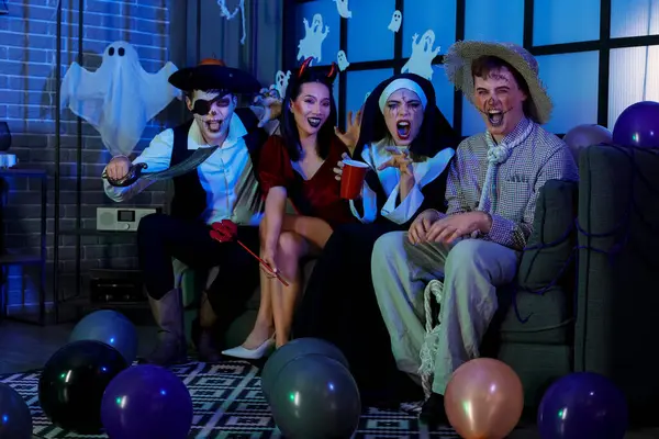 Group of friends in costumes sitting at Halloween party