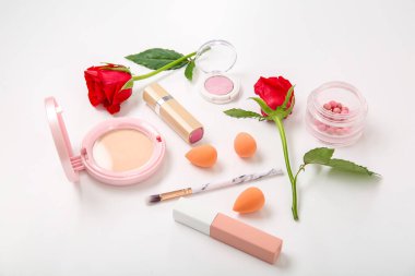 Makyaj ürünleri ve beyaz arkaplanda güzel kırmızı gül çiçekleri