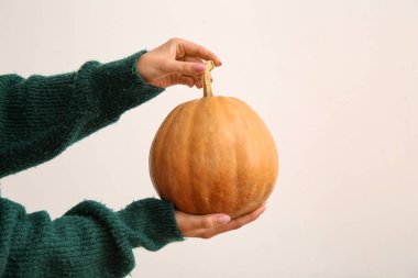 Beyaz arka planda cadılar bayramı kutlaması için çiğ balkabaklı kadın elleri