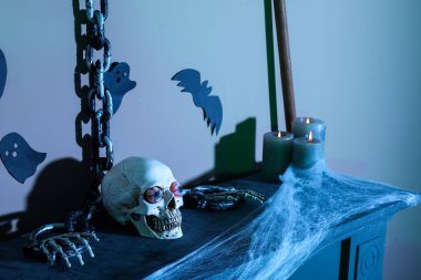 Cadılar Bayramı için dekore edilmiş şömine rafında zincirli kafatası ve mumlar.