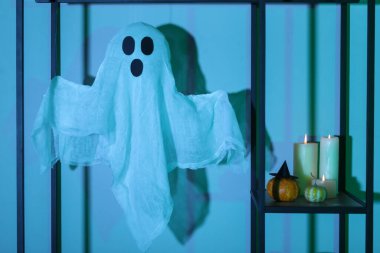 Cadılar Bayramı balkabaklarıyla raflar, mumlar ve karanlık salonda hayalet