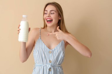 Bej arka planda sütü olan mutlu genç bir kadın.