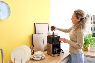 Mutfakta kahve yapan olgun bir kadın.