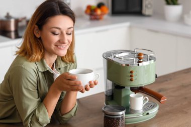 Mutfakta bir fincan sıcak kahveyle genç bir kadın.