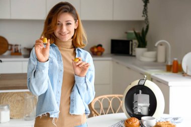 Mutfakta kahve makinesi ve kapsülleri olan genç bir kadın.