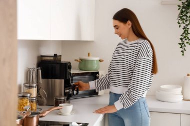 Genç bayan mutfakta kahve yapıyor.