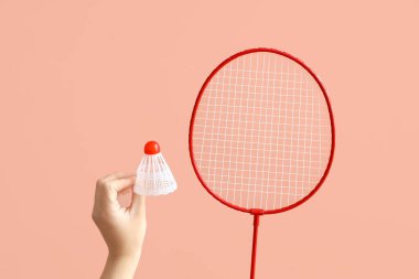 Pembe arka planda badminton raketi tutan bir kadın.