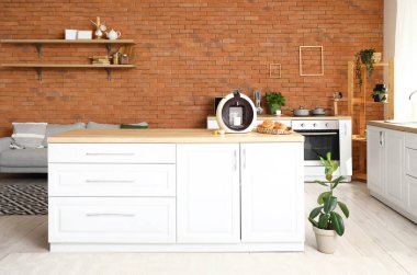 Mutfaktaki masada taze çörek ve kapsüllü modern kahve makinesi.