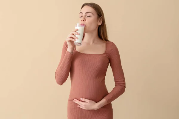 Młoda Ciężarna Kobieta Pijąca Mleko Beżowym Tle — Zdjęcie stockowe