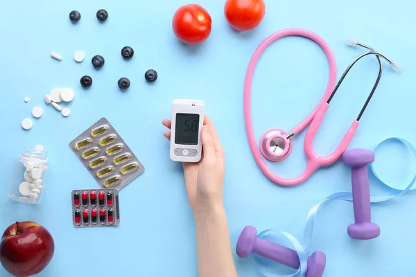 stock image Diabetic woman with glucometer, pills, food, stethoscope and dumbbells on blue background