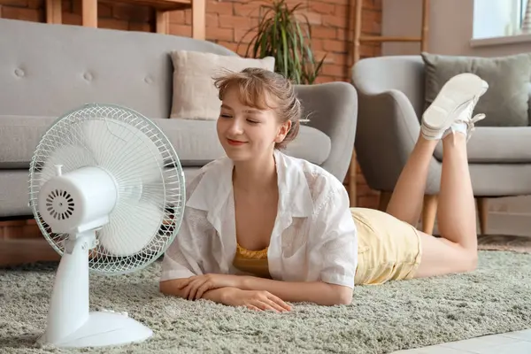 Young Woman Blowing Electric Fan Lying Floor Home — Stock Photo, Image