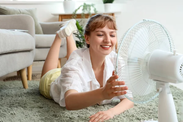 Young Woman Blowing Electric Fan Lying Floor Home — Stock Photo, Image