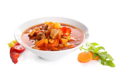 Bir kase lezzetli sığır güveci ve beyaz arka planda taze sebzeler.