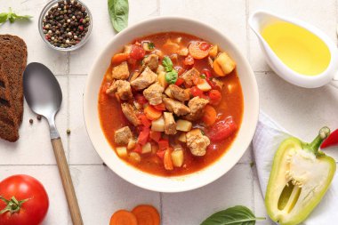 Bir kase lezzetli sığır güveci, sebze, yağ ve biber, beyaz fayanslı arka planda.