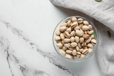 Beyaz arka planda fıstıklı cam kase.