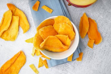 Beyaz arka planda kurutulmuş mango dilimleri ile kase