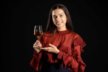 Siyah arka planda bir bardak şarabı olan genç bir kadın.