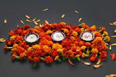 Siyah arka planda kadife çiçekleri olan mumlar yakmak. Divaly kutlaması