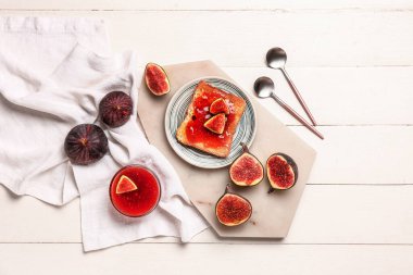 Beyaz ahşap zemin üzerinde tatlı incir reçeli ile bir tabak tost.