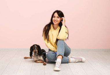 Pembe duvarın yanında oturan evcil hayvanı olan dişi köpek bakıcısı.