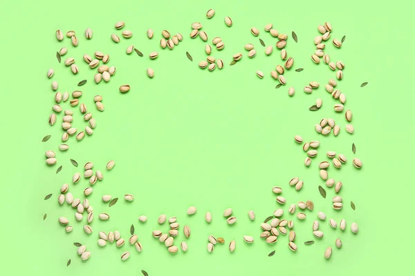 おいしいピスタチオナッツと緑の背景の葉で作られたフレーム — ストック写真