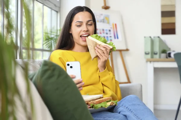 Νεαρή Γυναίκα Κινητό Τηλέφωνο Τρώει Νόστιμο Σάντουιτς Στο Σπίτι — Φωτογραφία Αρχείου