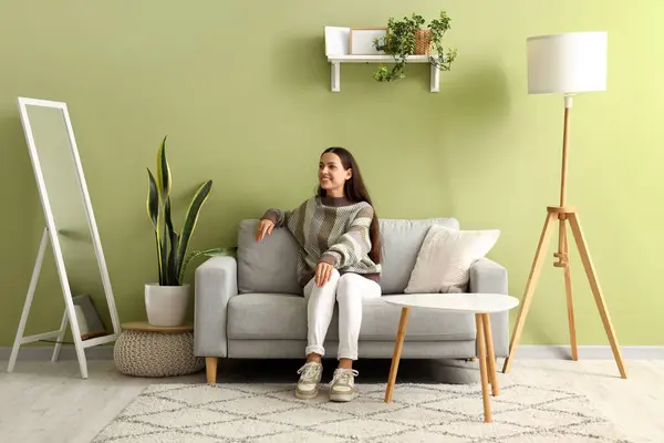 stock image Beautiful happy young woman sitting on sofa in living room