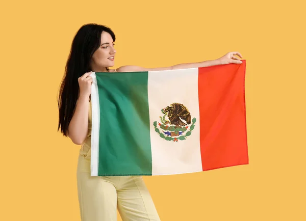黄色の背景にメキシコの旗を持つかなり若い女性 — ストック写真