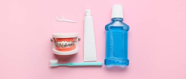 Diş teli, diş fırçası, yapıştırıcı ve ağız pembe arka planda durulama ile çene modeli