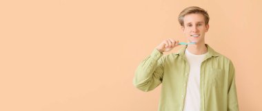 Diş telleri ve bej arka planda diş fırçası olan genç bir adam.