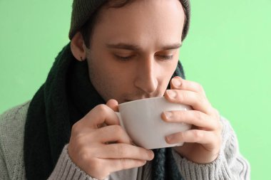 Yeşil arka planda çay içen genç adam, yakın plan.