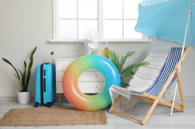 Şişme yüzük, bavul, plaj şemsiyesi ve iskemle oturma odasında.