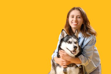 Sarı arka planda iri köpekli mutlu genç bir kadın.