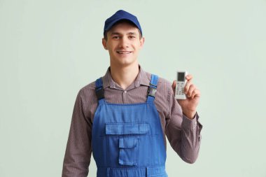 Klima uzaktan kumandalı erkek teknisyen yeşil arka planda