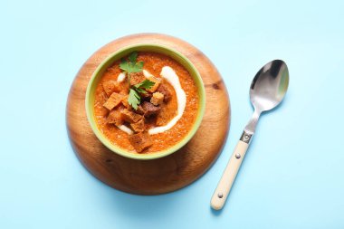 Bir kase lezzetli kremalı çorba ve mavi arka planda kızarmış ekmek.