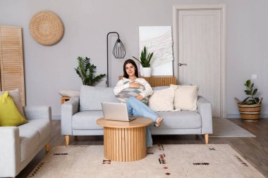 Oturma odasındaki kanepede oturan yastıklı genç kadın.