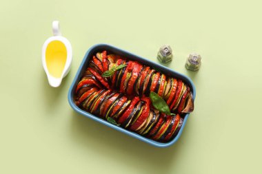 Lezzetli Ratatouille tabağı, baharatlar ve yeşil arka planda yağlı sos teknesi.