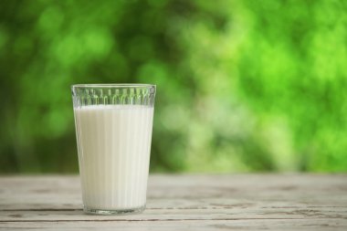 Dışarıdaki beyaz tahta masada bir bardak taze süt.