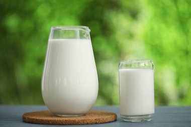 Dışarıdaki gri ahşap masada bir bardak taze süt.