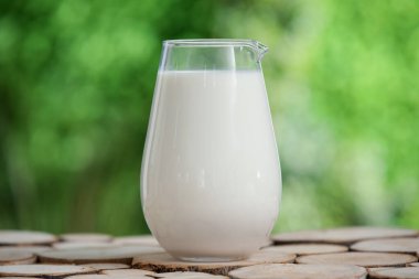 Dışarıdaki tahta masada bir sürahi taze süt.