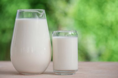 Dışarıdaki bej masada bir bardak taze süt.