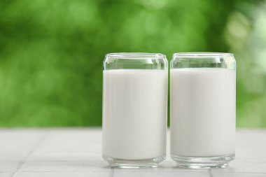 Dışarıdaki beyaz fayans masasında taze süt bardakları