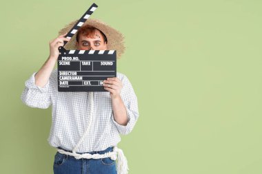 Cadılar Bayramı için yeşil arka planda el çırpmalı korkuluk gibi giyinmiş yakışıklı genç adam.