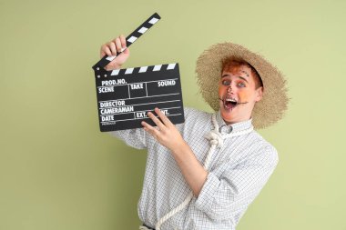 Cadılar Bayramı için yeşil arka planda el çırpmalı korkuluk gibi giyinmiş yakışıklı genç adam.